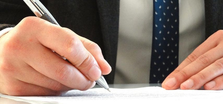 mężczyzna podpisujący umowę